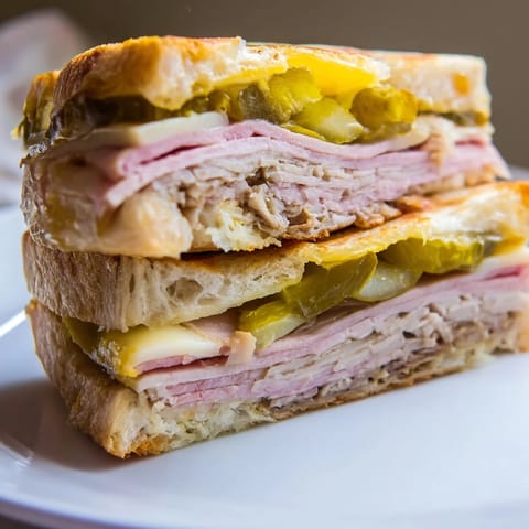 Sliced diagonally to reveal savory layers of pork, ham, and pickles on a classic Cuban sandwich.