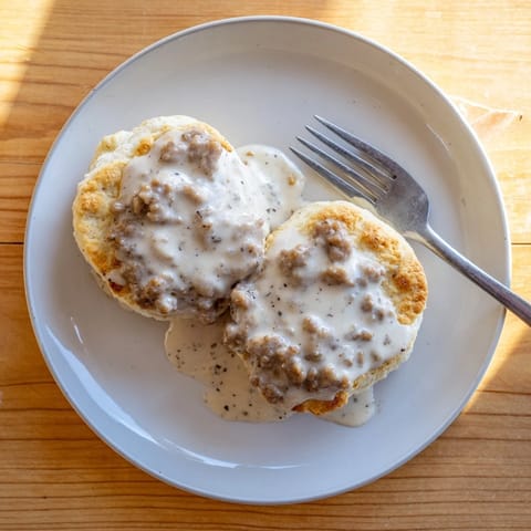 Freshly baked biscuits and gravy topped with crumbled sausage and a drizzle of rich gravy, ideal for weekend brunch.