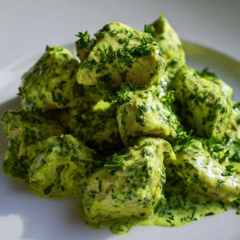 A close-up of Green Goddess Chicken Salad, featuring juicy chicken tossed in vibrant green dressing, served over a bed of fresh salad greens and vegetables.