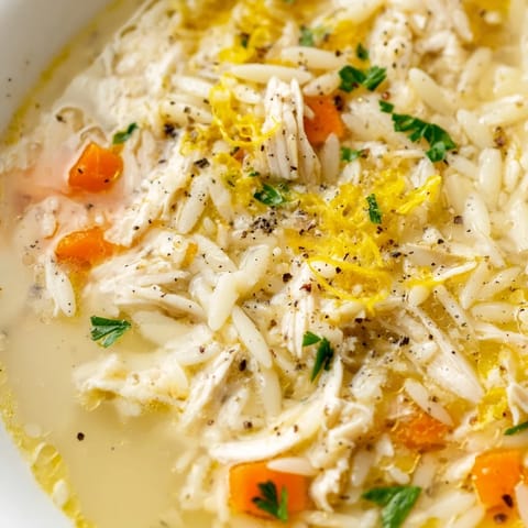 Bright and zesty Lemon Pepper Chicken Orzo Soup with tender shredded chicken, carrots, and orzo pasta in a clear broth.
