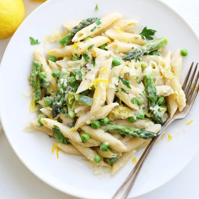 Garlic Parmesan Spring Vegetable Pasta served in a white bowl, topped with extra Parmesan, lemon zest, and vibrant spring vegetables.