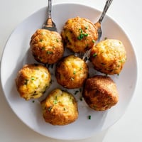 Golden, crispy Hushpuppies fresh from the fryer, resting on paper towels to drain excess oil.