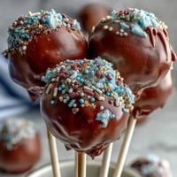 Festive graduation cake pops in school colors, decorated with shimmering gold sprinkles and ready to celebrate.