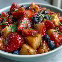 Bright strawberry lemonade fruit salad with juicy berries, tropical pineapple, and a tangy citrus glaze, perfect for a summer picnic.